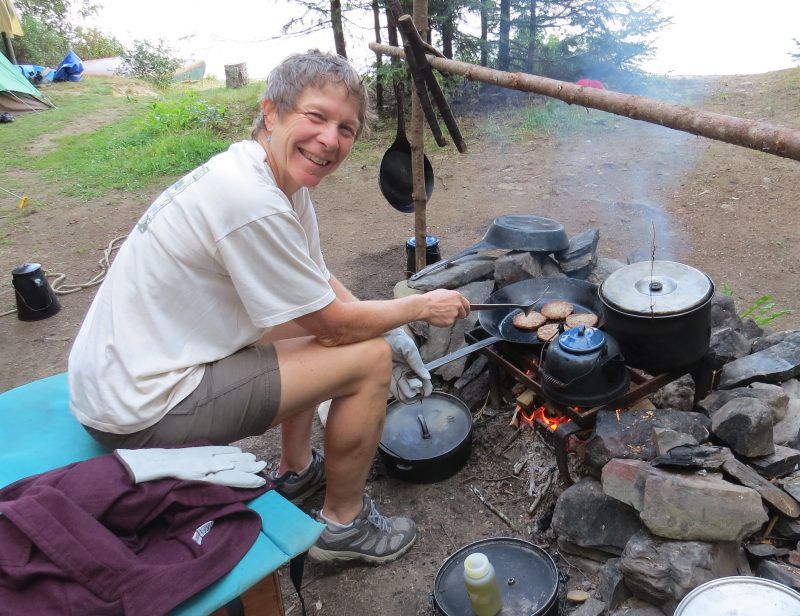 Cooking a delicious dinner at rustic canoe camping site on Allagash River. Guide Sandy Peplau summer